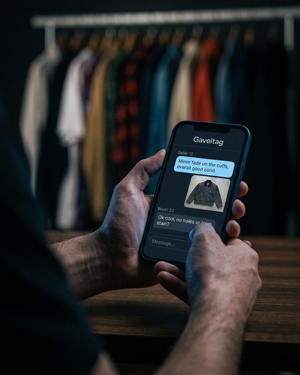 A phone on a reseller's desk at night, its screen lighting the jackets and tags around it