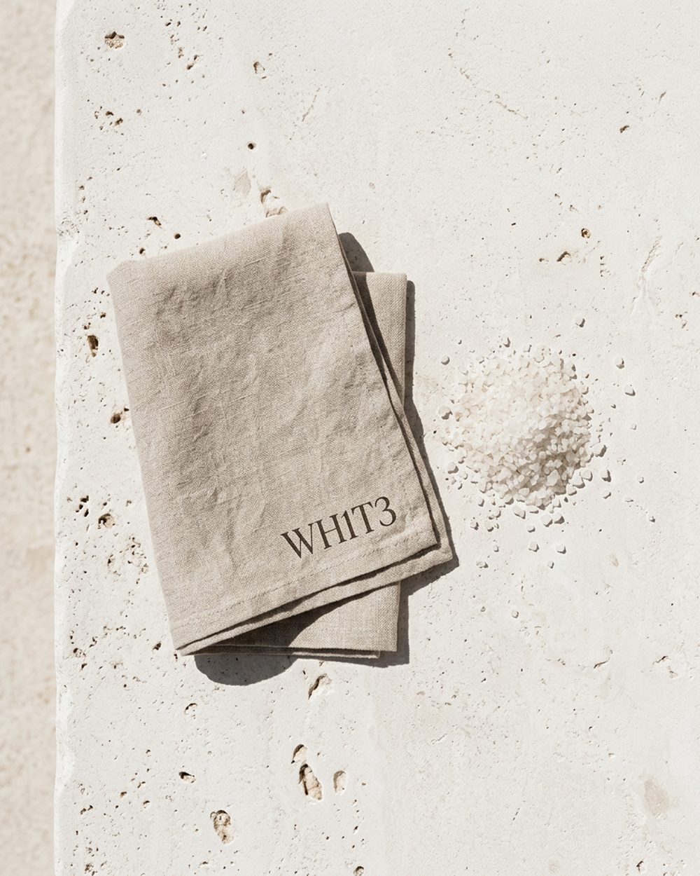 Coarse salt scattered across a fold of pale linen in soft daylight