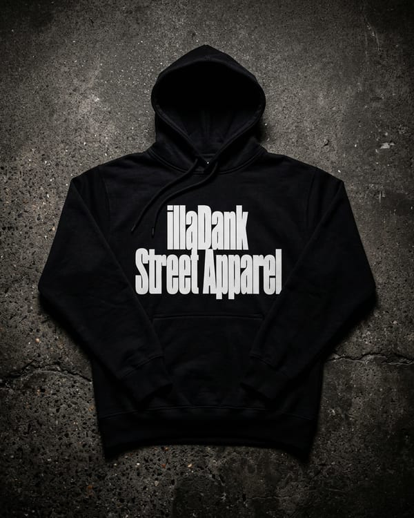 illaFlo Records Wordmark Hoodie — black heavyweight hoodie with bold near-white chest wordmark, worn against a dark brick wall at night