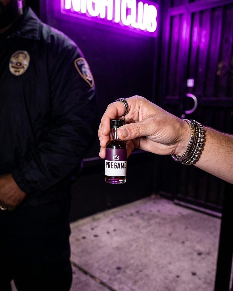 Waiting outside a bar door at night with a Pre Game shot