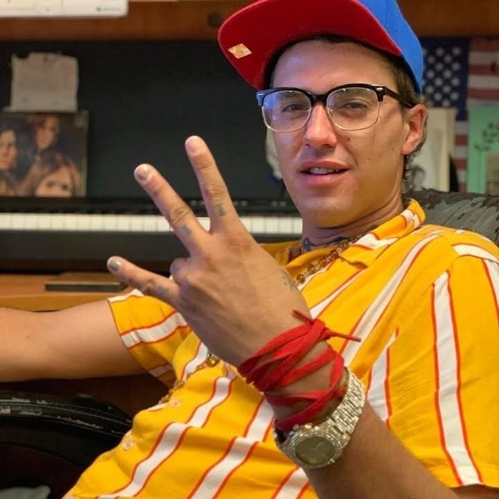 $HELTA throwing a peace sign in the studio, piano behind him