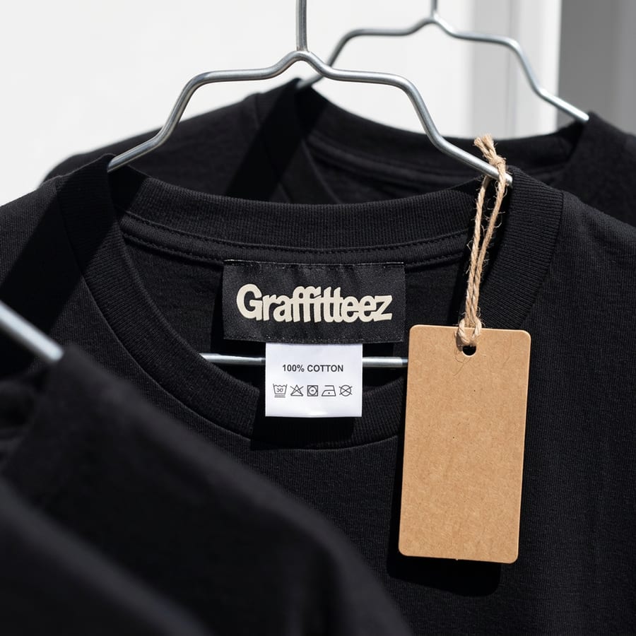 Close shot of a garment's permanent label and care tag stitched inside a black tee