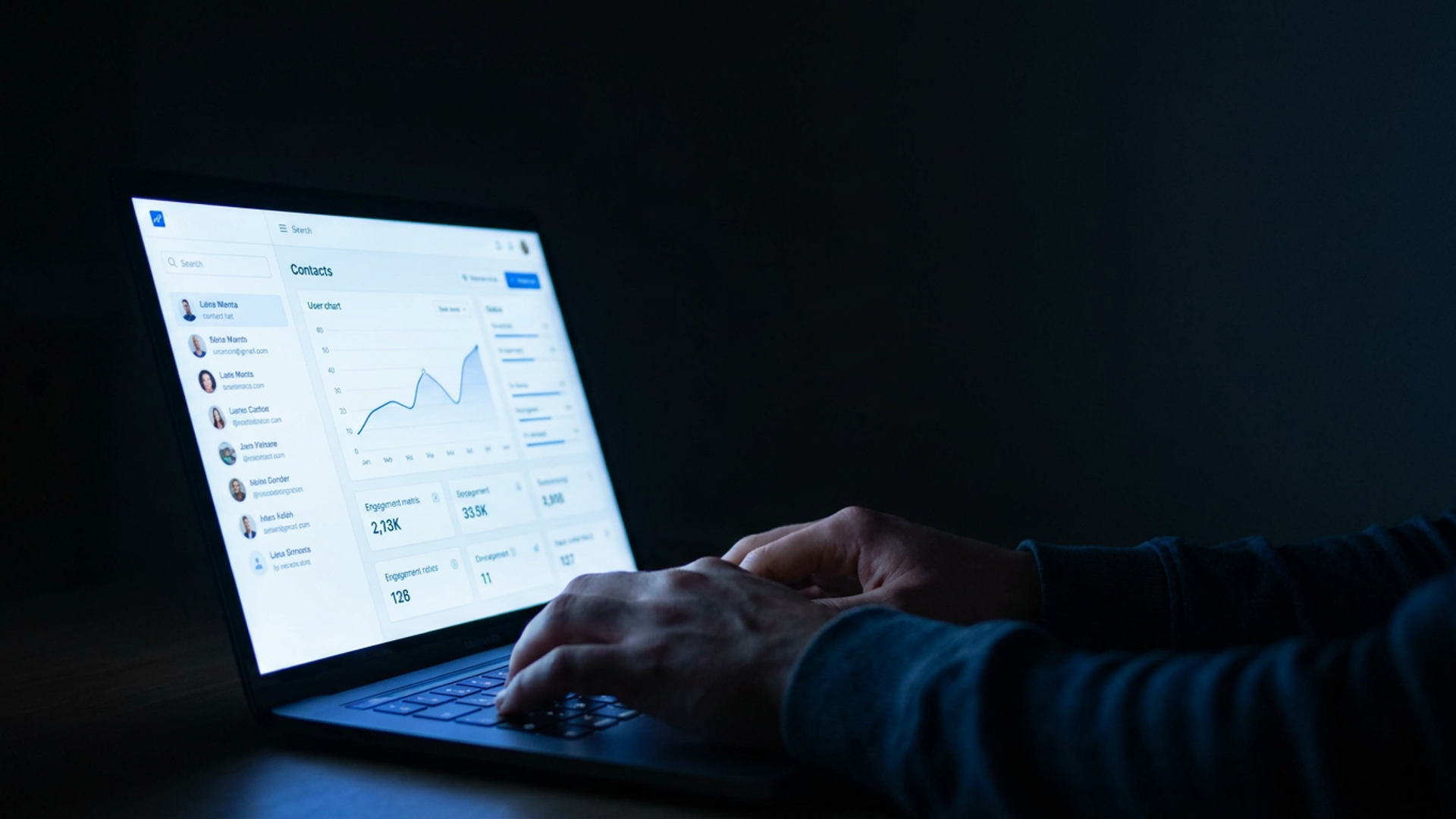 Solo founder reviewing an influencer contact list on a glowing laptop screen in a dark home office, cool blue light, late